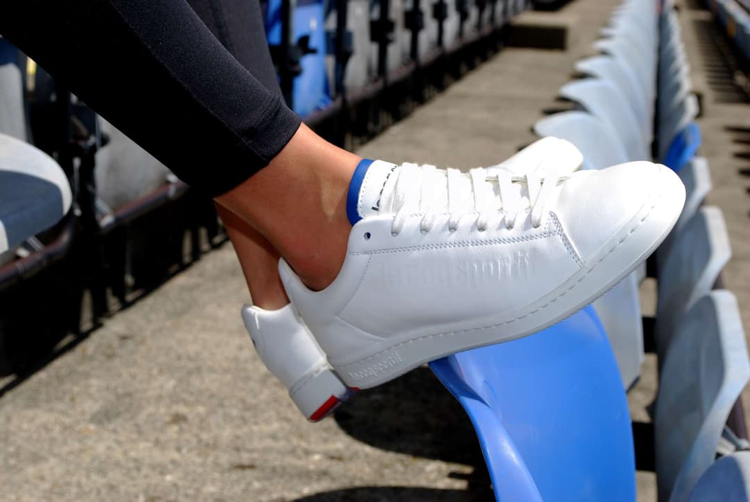 Sneaker Blazon blanc de Le Coq Sportif aux couleurs bleu et rouge du FC Lausanne-Sport, portée avec un bracelet bleu