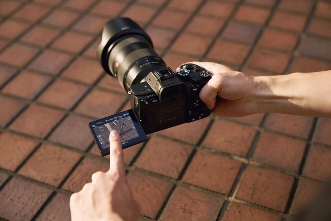 Sony Alpha 7S III tenu en main avec écran tactile déplié, montrant l'interface de la caméra professionnelle