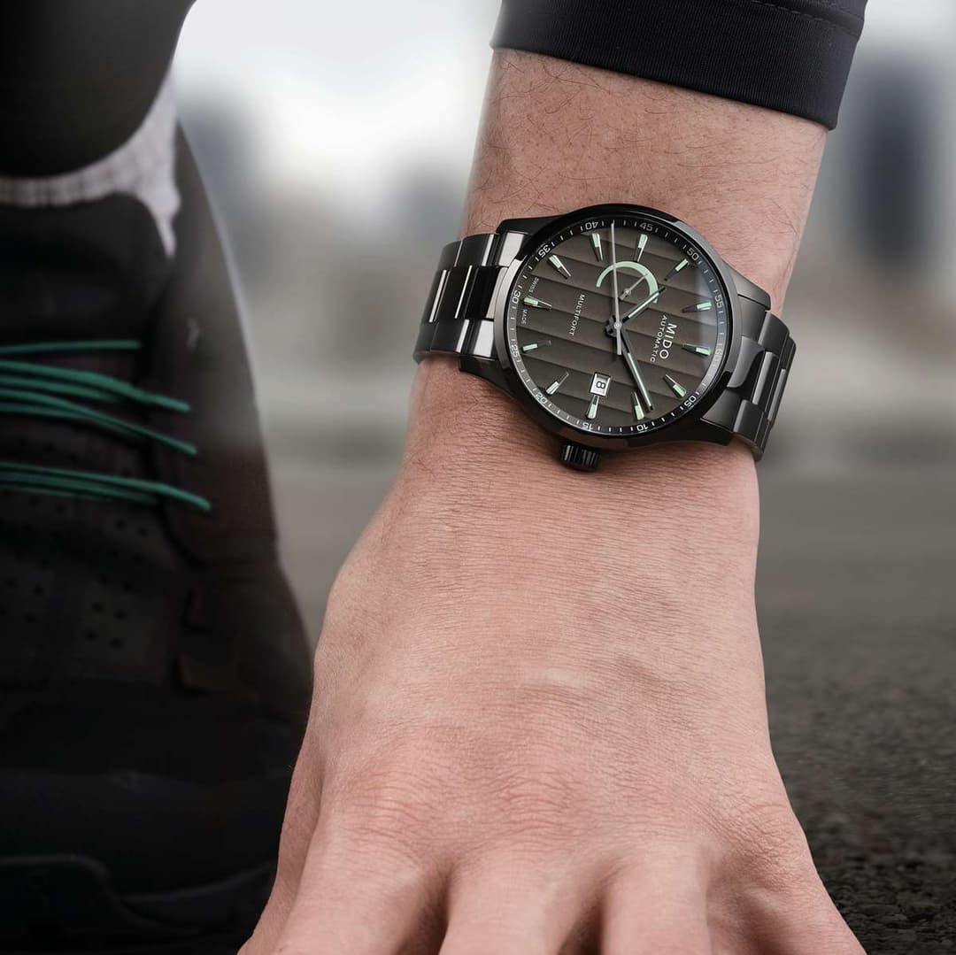 Montre Mido Multifort au cadran noir avec indicateur d'autonomie vert à 3 heures, portée au poignet