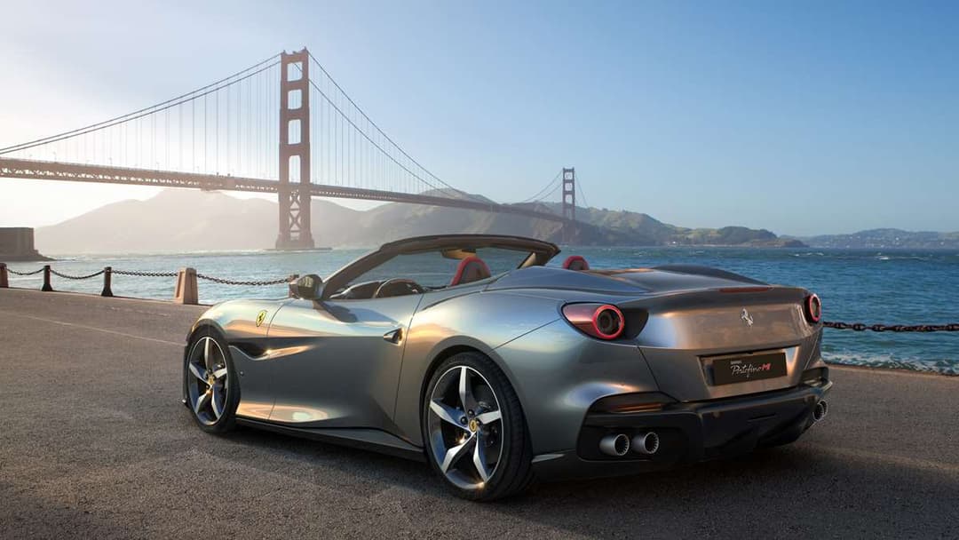 Ferrari Portofino M décapotable gris argent face au Golden Gate Bridge à San Francisco, design sportif renouvelé avec intérieur rouge