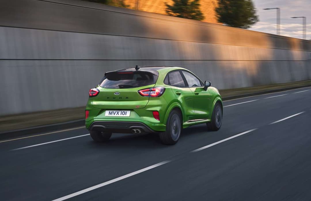 Ford Puma ST vert vif en mouvement sur une autoroute, vue de trois-quarts arrière