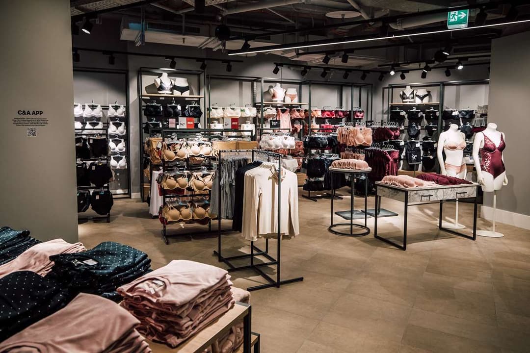 Intérieur du nouveau magasin C&A avec présentoirs de vêtements, mannequins et mobilier moderne dans une atmosphère épurée aux tons neutres