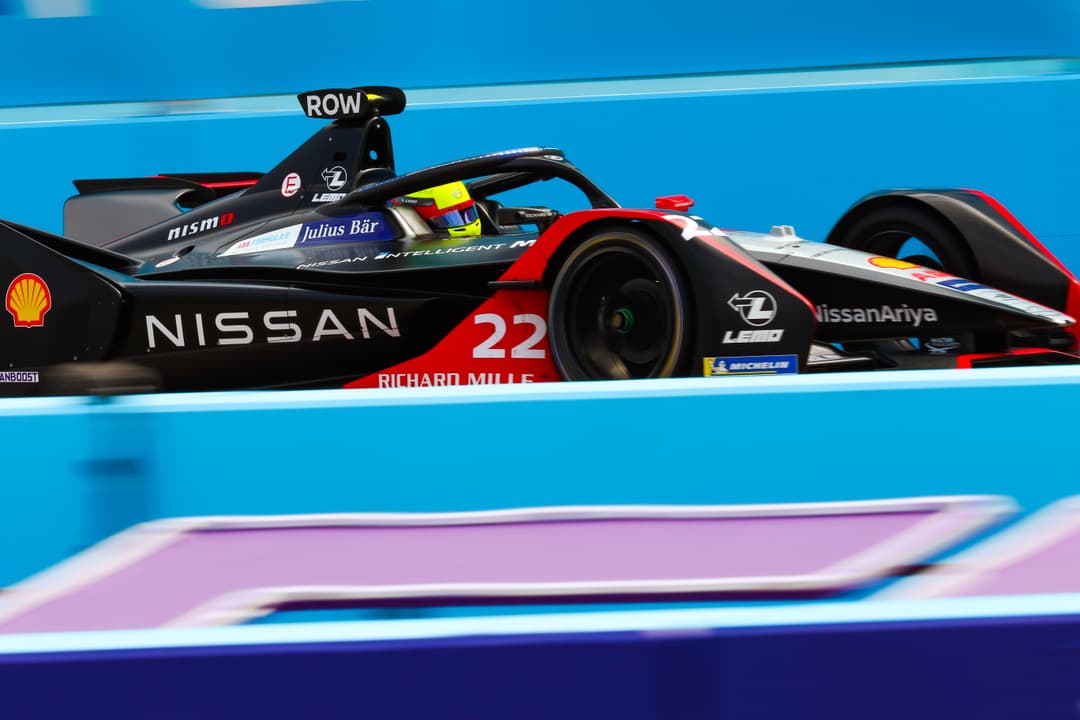 Voiture de course Nissan e.dams numéro 22 de Formule E, noire et rouge, sur un circuit avec barrière bleue