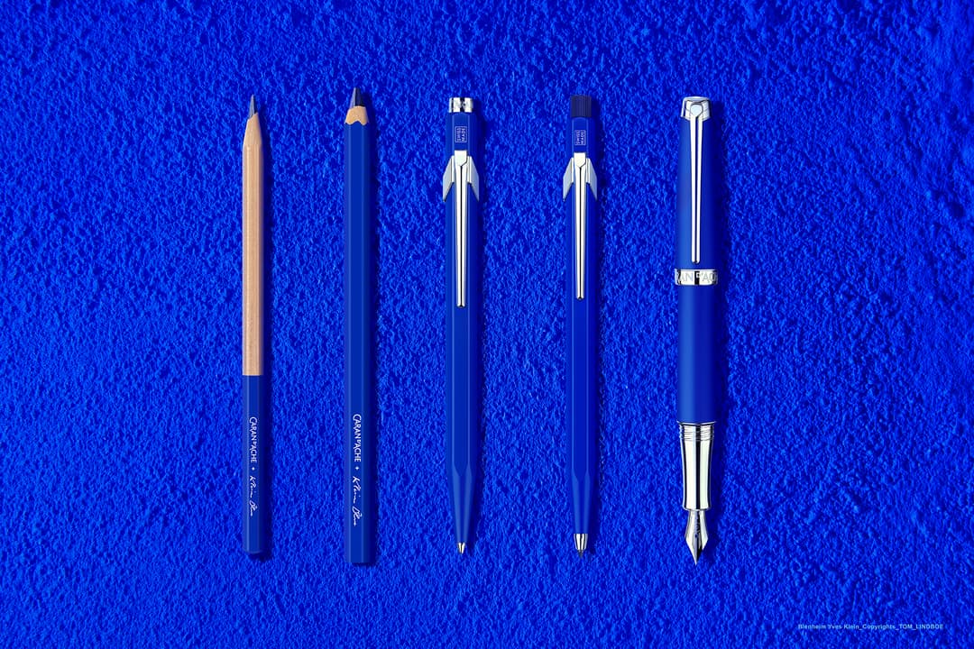 Collection Caran d'Ache Klein Blue® : cinq instruments d'écriture bleu outremer et dorés alignés sur fond bleu