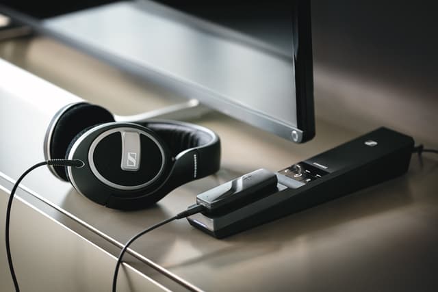 Casque audio Sennheiser noir avec arceau et écouteurs en cuir, posé à côté d'une télécommande noire