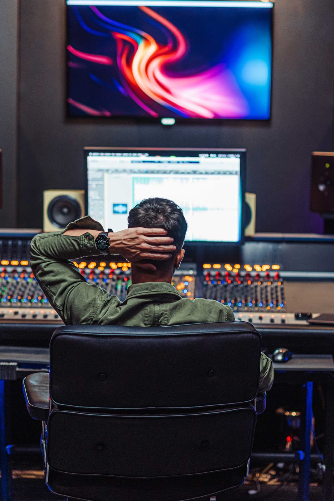 Producteur musical en studio d'enregistrement, face aux écrans et console de mixage, montre HUAWEI au poignet