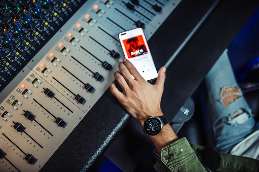 Luca Hänni tenant un HUAWEI P40 Pro affichant un contenu en direct au-dessus d'une console de mixage audio en studio