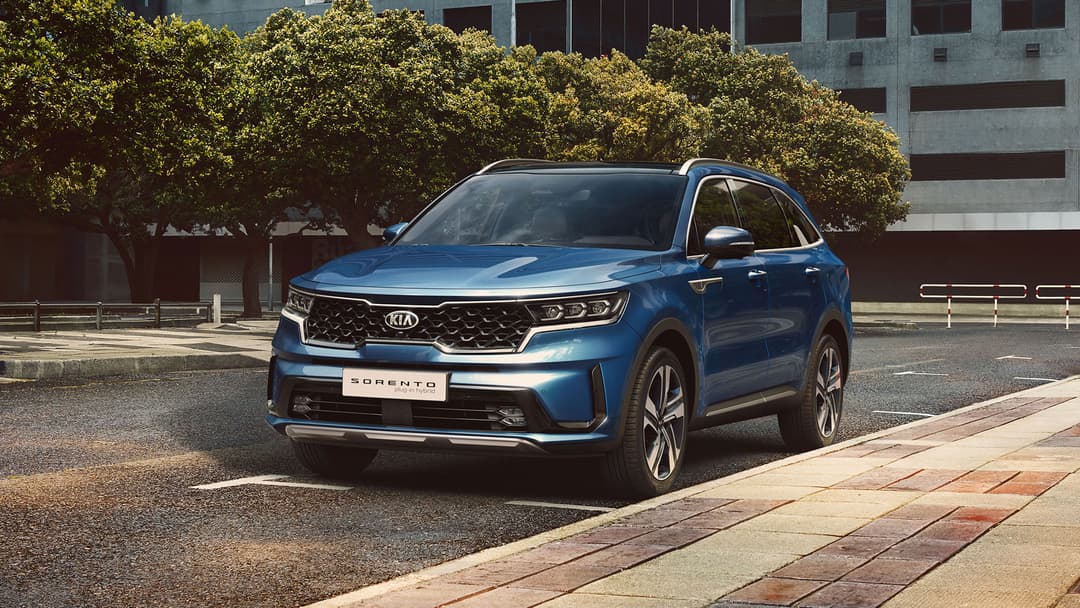 Kia Sorento bleu métallisé garé sur une place urbaine avec bâtiments en arrière-plan