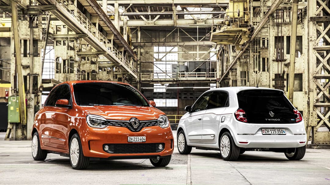 Renault Twingo Electric orange et blanche côte à côte dans un entrepôt industriel désaffecté