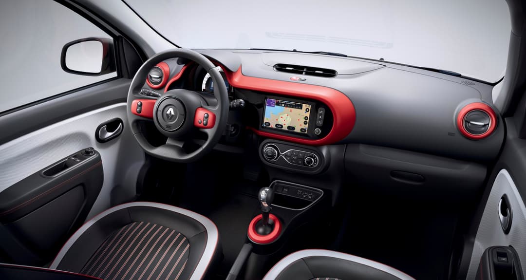 Intérieur de la Renault Twingo Electric avec volant, tableau de bord rouge et noir, écran tactile de navigation et sièges à surpiqûres contrastées
