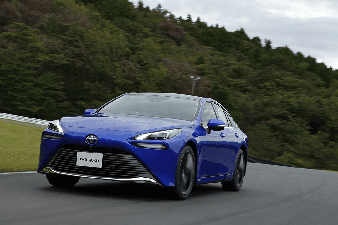 Nouvelle Toyota Mirai bleue électrique circulant sur une route, forêt en arrière-plan
