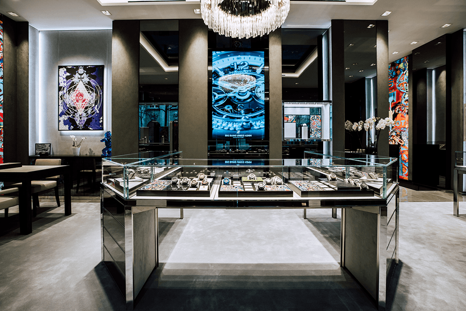 Boutique Hublot à Zurich avec vitrines de montres en verre, murs en marbre noir et gris, écrans numériques et luminaires design