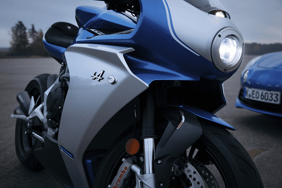 Moto MV Agusta blanche et bleue avec logo A en relief, sièges Alcantara noir et coutures bleues, drapeaux français et italien sur le garde-boue
