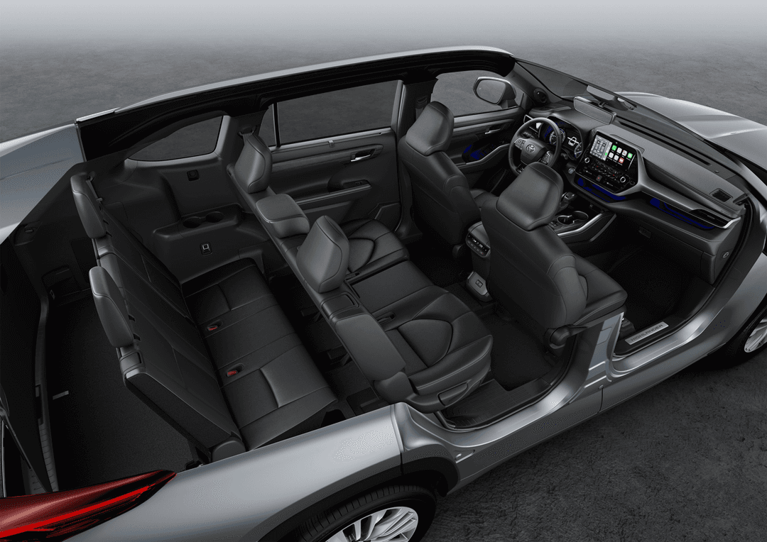 Habitacle du Toyota Highlander avec sièges en cuir noir, volant et tableau de bord avec écran tactile, vue d'ensemble des trois rangées de sièges