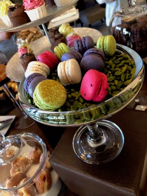 Coupe en verre remplie de macarons de différentes couleurs et de pistaches, entourée d'autres pâtisseries au Beau-Rivage Palace