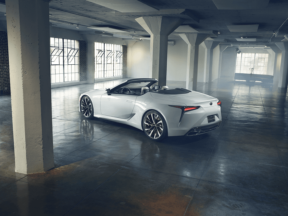 Lexus LC 500 cabriolet blanc avec toit rétractable ouvert, garé dans un garage moderne bien éclairé