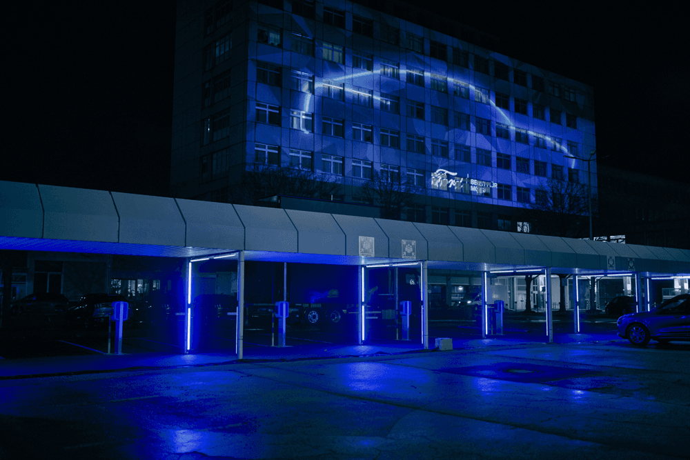 Bâtiment illuminé en bleu la nuit avec enseigne Ford, façade moderne aux vitres teintées et architecture épurée