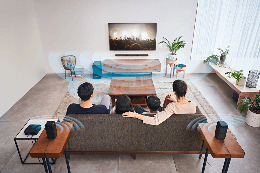 Famille assise sur un canapé face à un téléviseur, avec système audio Sony HT-S40R et enceintes surround positionnées autour du salon