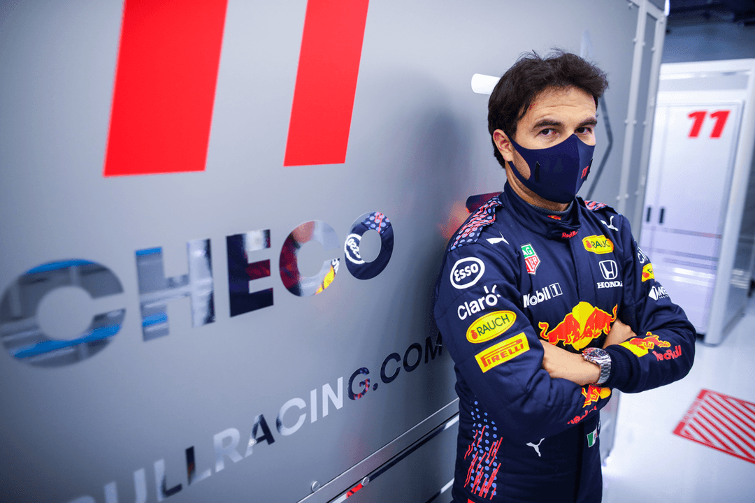 Pilote Red Bull Racing Honda en combinaison bleu marine aux couleurs de l'équipe, portant un masque bleu marine et une montre TAG Heuer