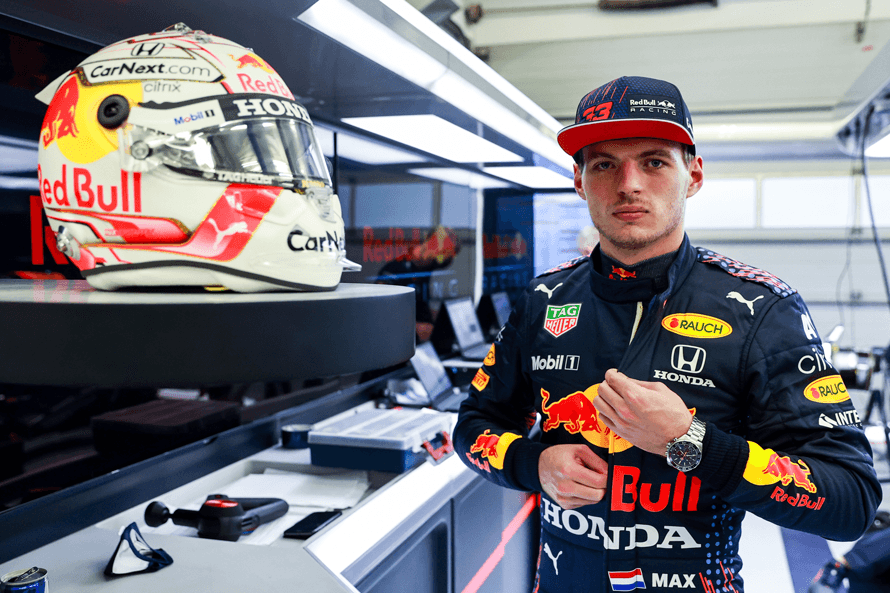 Max Verstappen en combinaison Red Bull Racing Honda avec montre TAG Heuer, à côté de son casque rouge et blanc