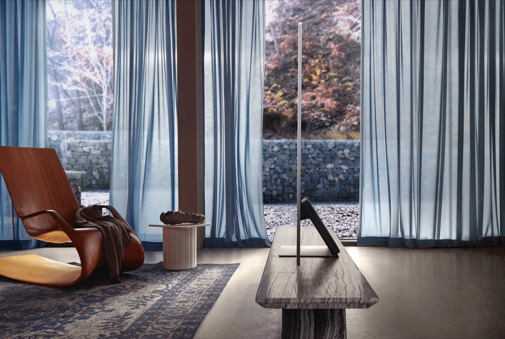 Téléviseur Samsung Neo QLED sur pied dans un salon moderne avec baies vitrées et mobilier design