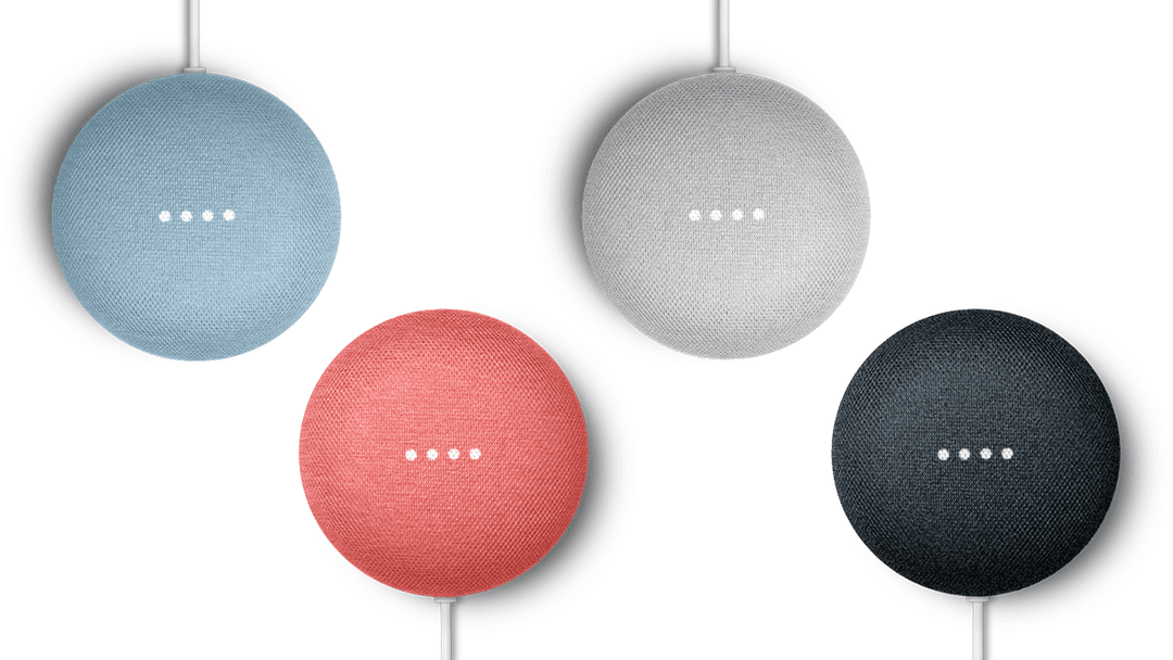 Quatre enceintes Google Nest Mini de couleurs différentes : bleu ciel, gris clair, rose corail et noir, suspendues avec des câbles