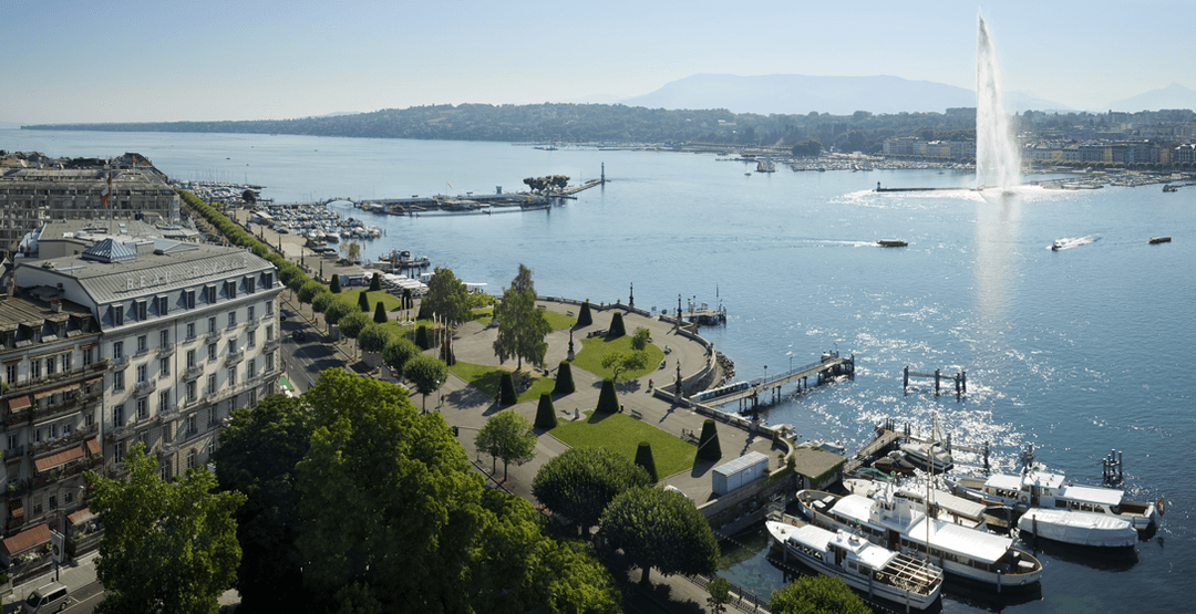 Aérienne du lac Léman à Genève avec le jet d'eau, les berges aménagées et l'hôtel Beau-Rivage en premier plan