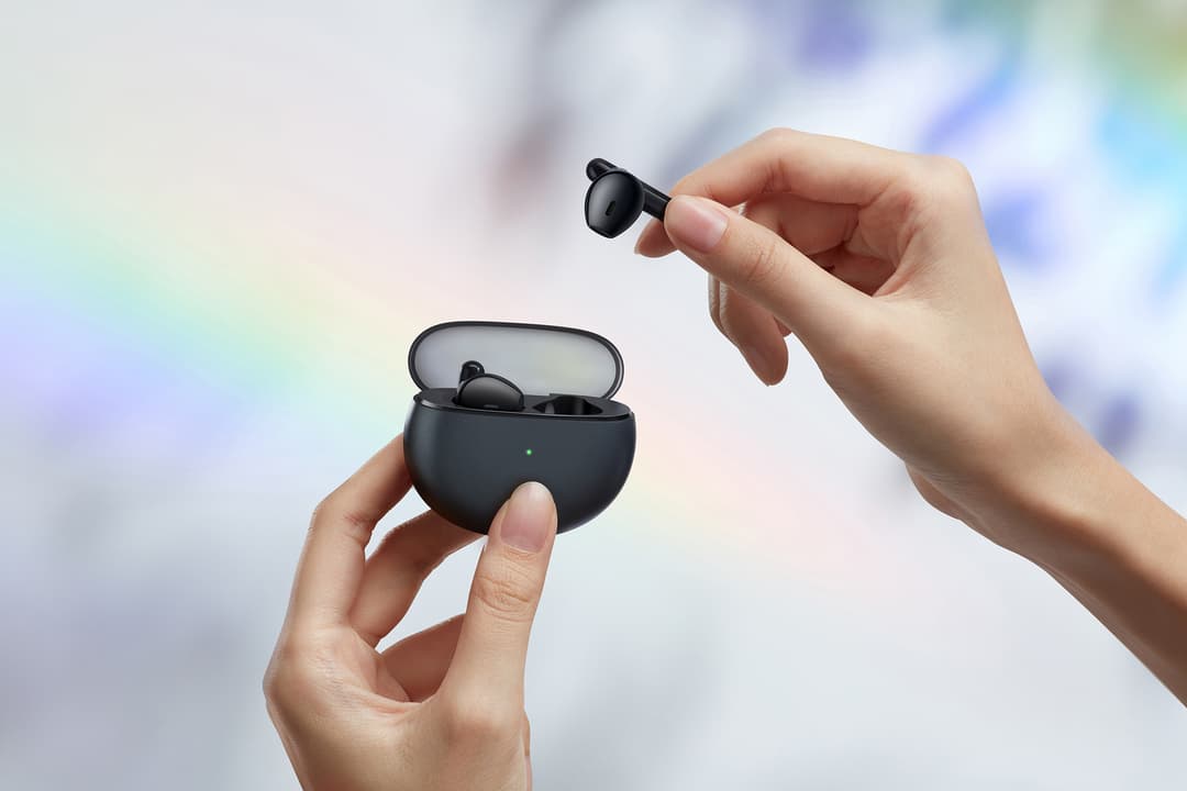 Écouteurs OPPO Enco Air noirs, l'un sortant du boîtier de charge tenu dans les mains