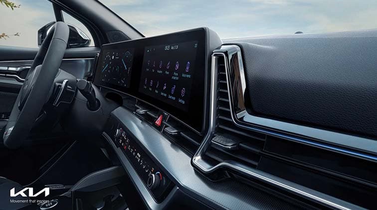 Habitacle du Kia Sportage avec écran tactile horizontal, volant noir et tableau de bord moderne en teintes sombres