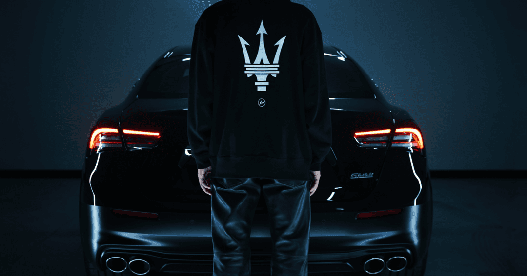 Deux Maserati Ghibli noires avec phares allumés encadrant un sweat noir orné du logo trident Maserati et Fragment