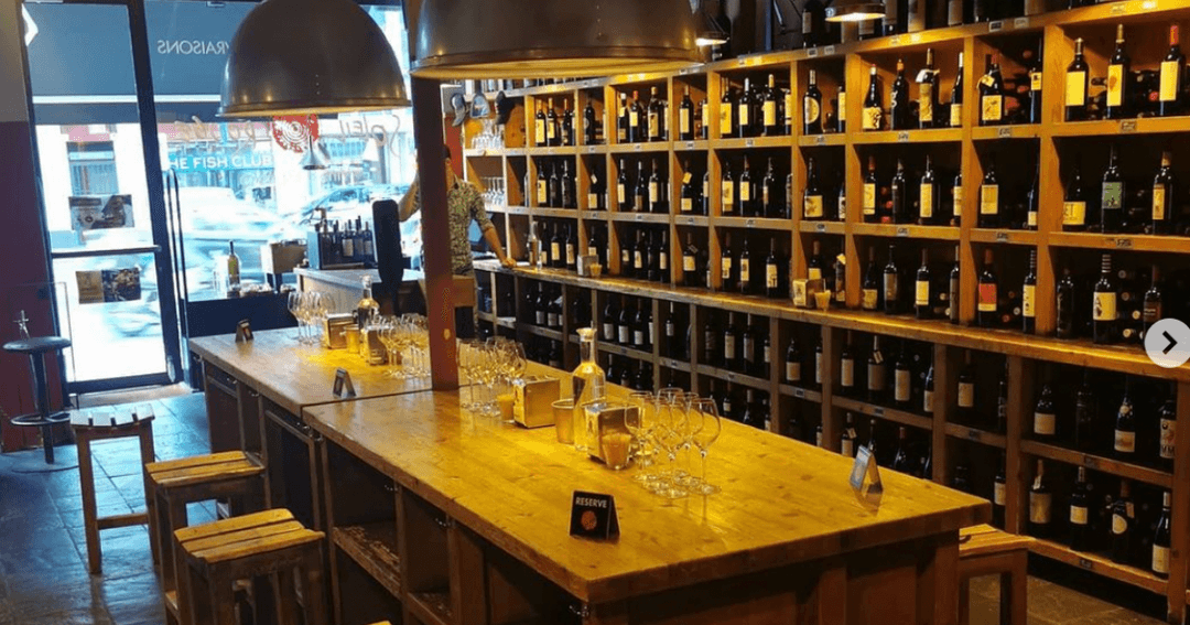 Intérieur du Soleil Rouge à Genève avec bar en bois, verres et étagères en bois garnies de plus de 400 bouteilles de vin espagnol