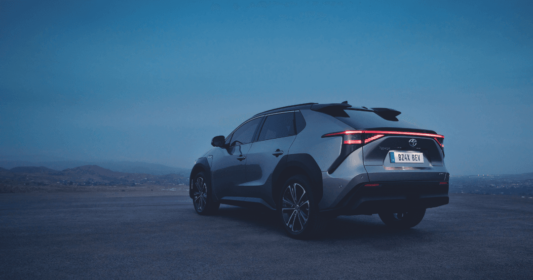 Toyota BZ4X, SUV électrique blanc et noir, photographié de profil sur une route en montagne au crépuscule