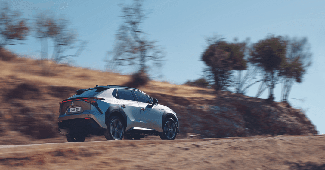 Toyota BZ4X blanc et bleu en mouvement sur route désertique, équipé d'un toit solaire