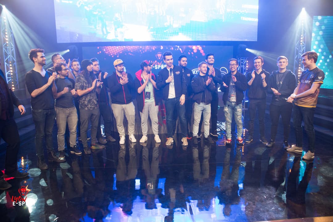 Équipes esport alignées sur scène lors du tournoi Lyon Esport 2018, avec écrans géants en arrière-plan et éclairage bleu