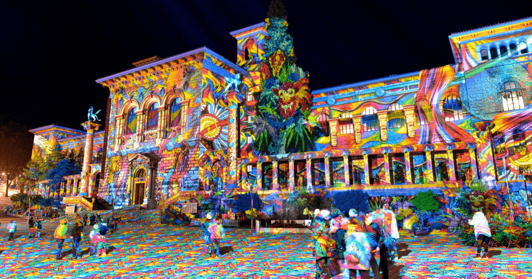 Bâtiments du centre-ville de Lausanne illuminés de projections colorées multicolores lors du festival Lausanne Lumière, avec des visiteurs déambulant sur la place