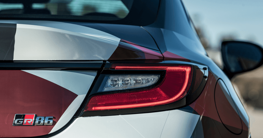 Détail du feu arrière LED rouge et blanc de la Toyota GR86, avec logo GR86 visible sur la carrosserie bicolore rouge et blanche