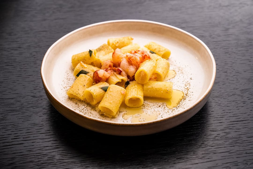 Pâtes Barilla AL BRONZO servies dans une assiette beige, avec sauce crémeuse, crevettes et herbes aromatiques
