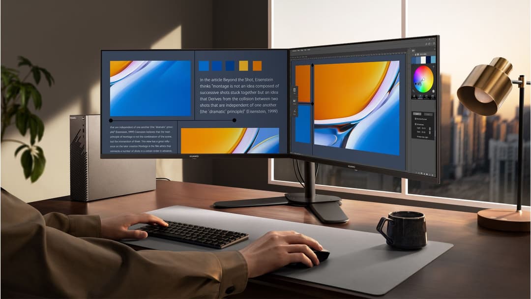 Poste de travail Huawei avec double écran affichant des contenus créatifs bleu et orange, clavier, souris et accessoires de bureau