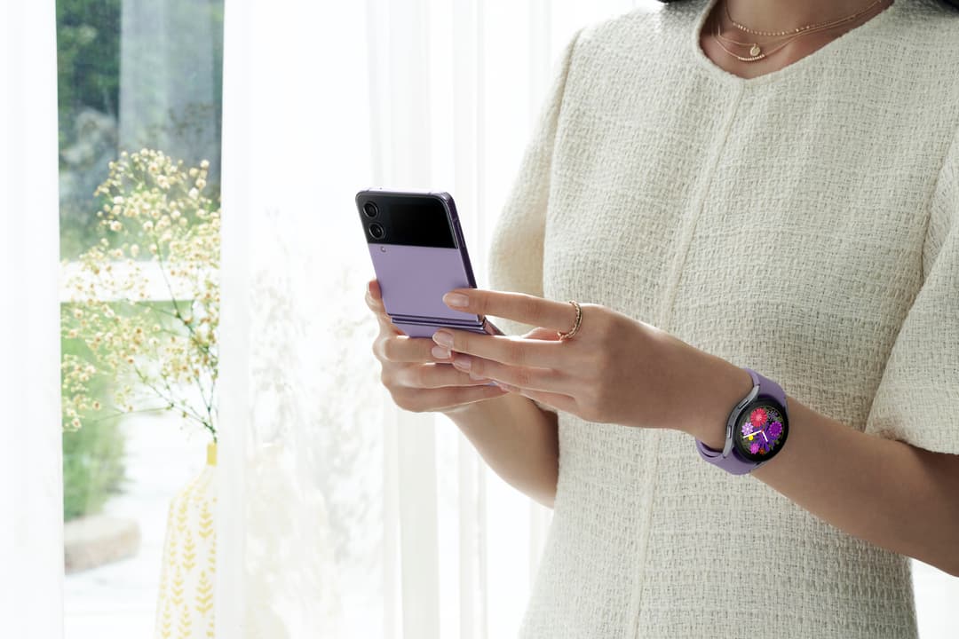 Femme tenant un téléphone Galaxy Flip violet à l'écran fermé, portant une Galaxy Watch5 Pro avec bracelet violet au poignet