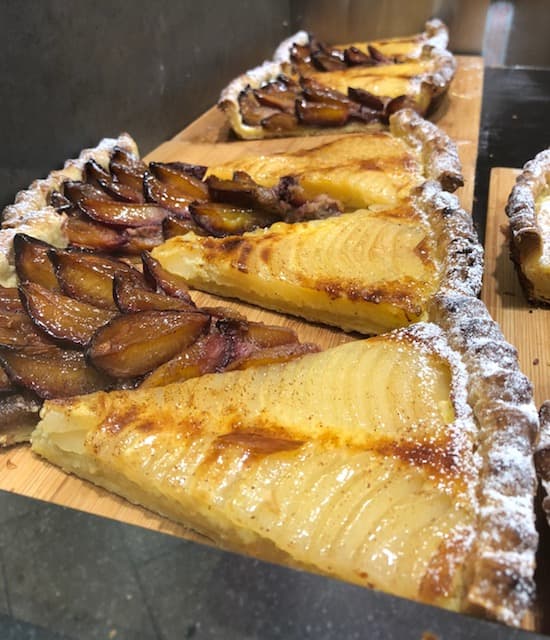 Tartes aux poires avec lamelles caramélisées et poudre de sucre, alignées sur une planche en bois