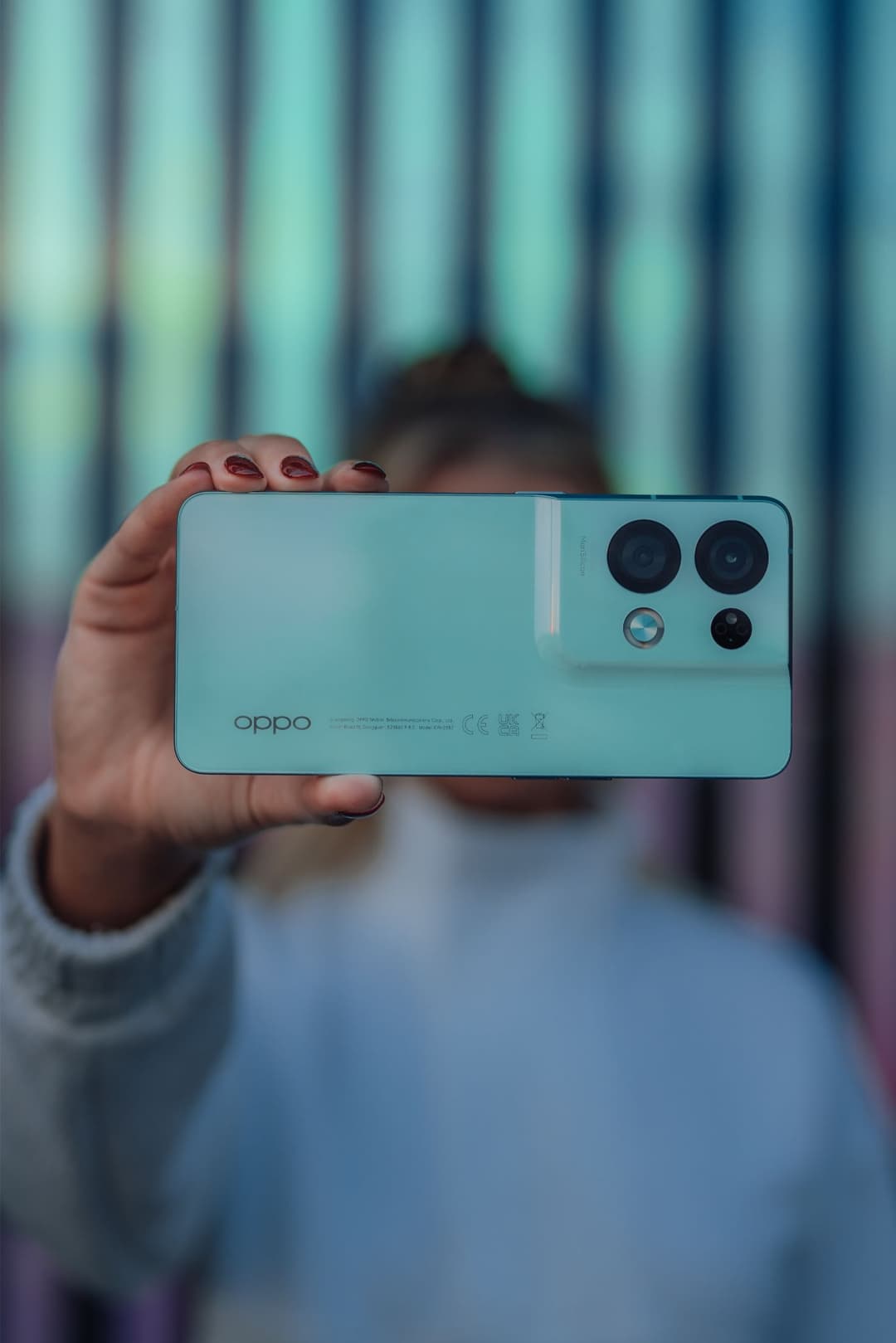 Smartphone OPPO Reno8 turquoise tenu en main, affichant son système de caméras arrière