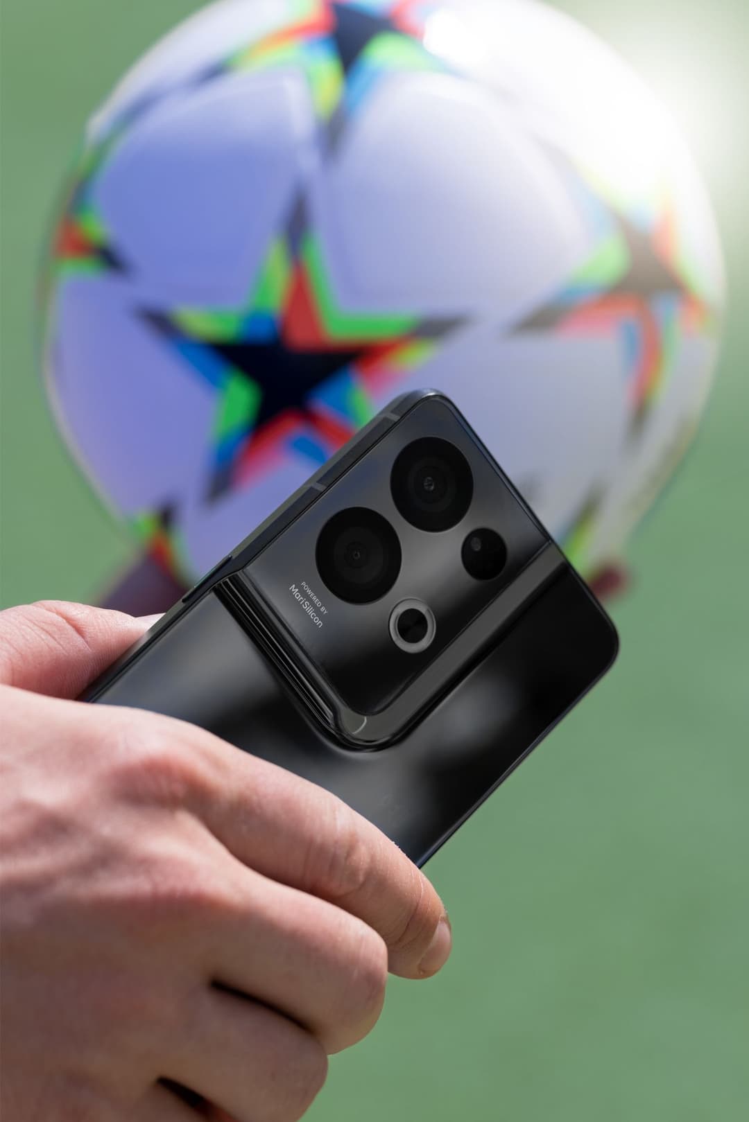 OPPO Reno8 Pro 5G noir avec son module caméra quatre objectifs, tenu en main devant un ballon coloré
