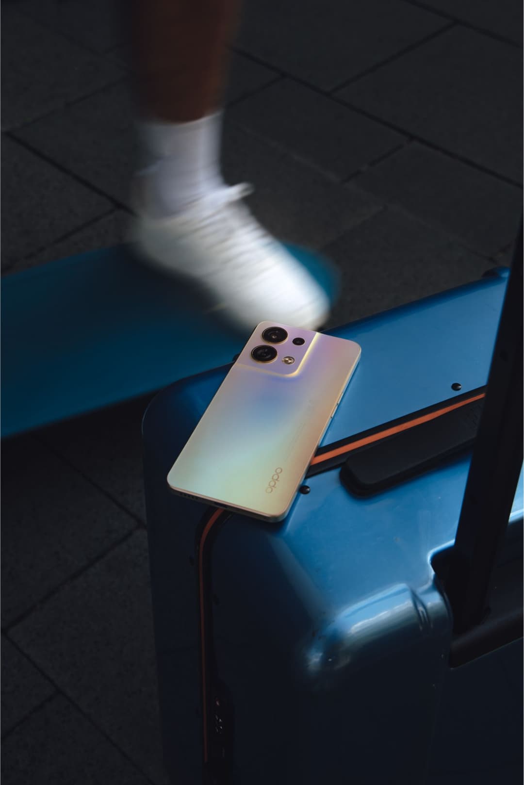 Smartphone OPPO Reno8 5G en couleur Shimmer Gold avec finition dégradée, posé sur un support bleu, montrant son dos avec module photo