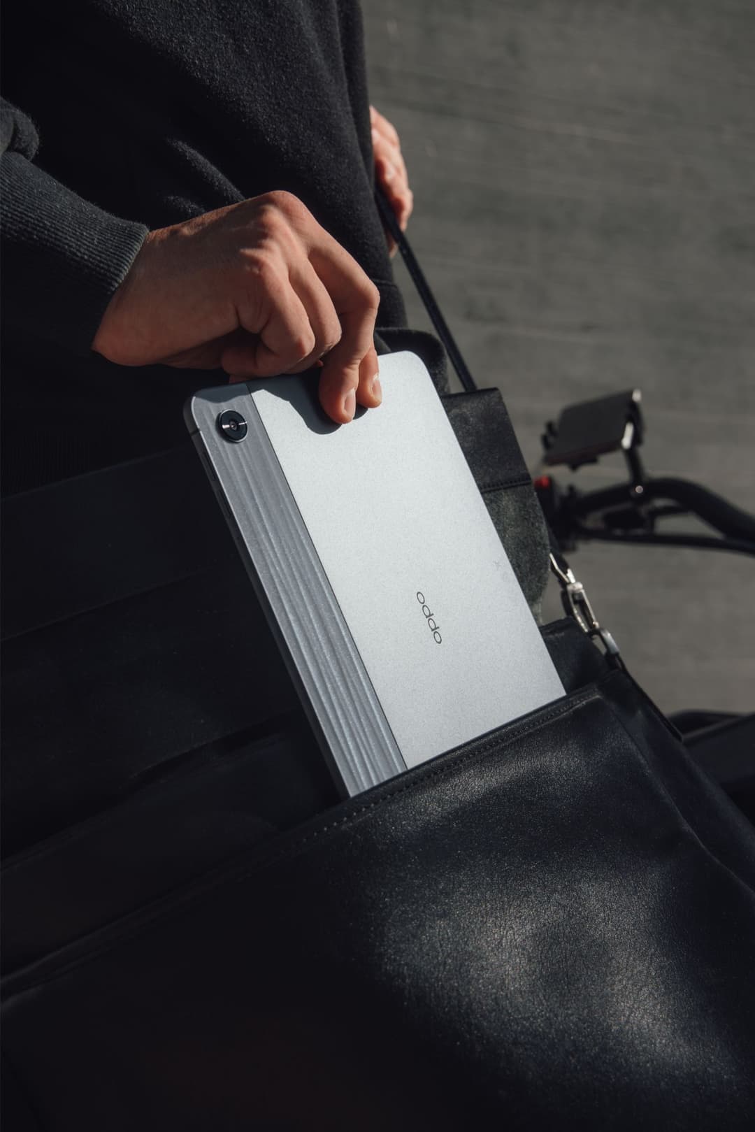 OPPO Pad Air blanc avec finition texturée en rainures, tenu à la main montrant sa prise ergonomique, dans un sac noir