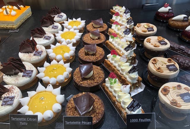 Vitrine de pâtisserie avec tartelettes au citron, tartelettes à la noix de pécan, mille-feuilles et petits gâteaux au chocolat et fruits rouges