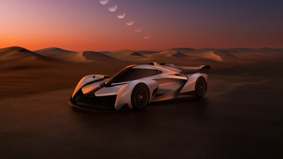 McLaren Solus GT blanche et noire dans un désert au coucher de soleil, vue de profil avec dunes de sable en arrière-plan