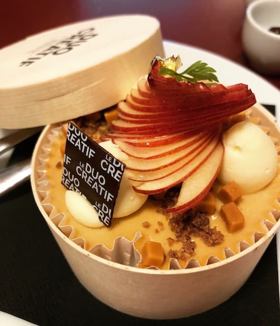 Vacherin Mont-d'Or garni de tranches de pomme, boules de glace et éclats de crumble, présenté dans sa boîte en bois traditionnelle