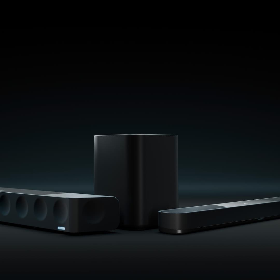 Barre de son Sennheiser Ambeo noire avec caisson de basses cylindrique et deux modules latéraux sur fond sombre