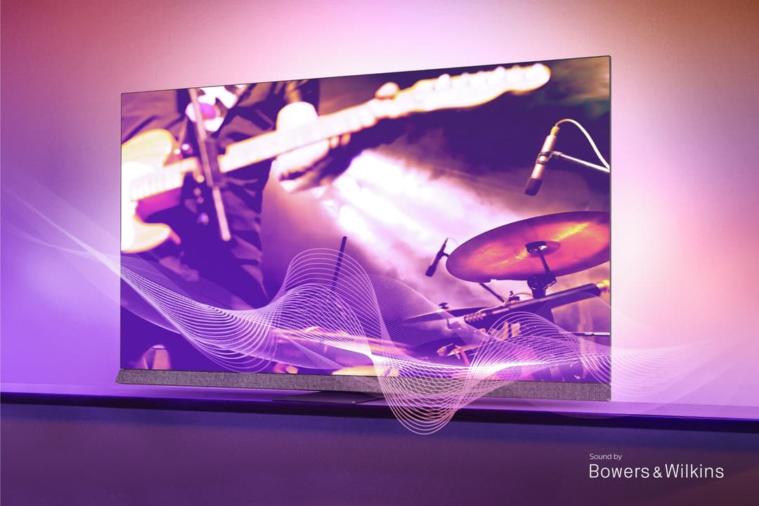 TV Philips OLED+907 affichant une scène musicale avec instruments en teintes violettes, socle en cuir, éclairage Ambilight rose ambiant