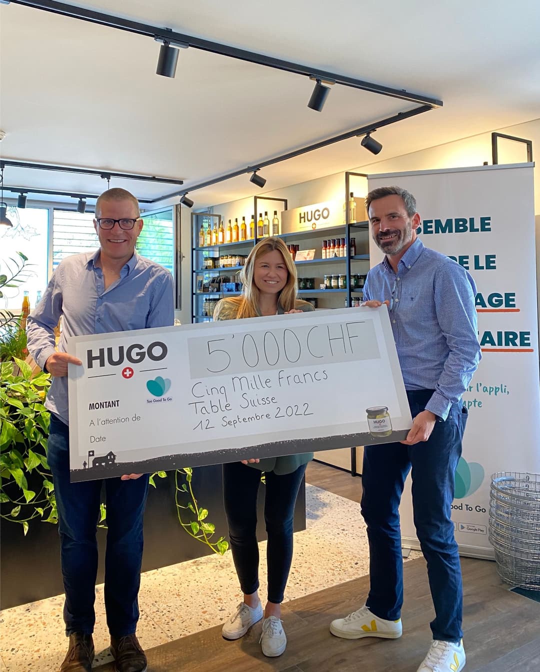 Trois personnes au Hugo Shop d'Aigle présentent un chèque de 5000 francs pour la Fondation Table Suisse, lors de la remise du don de septembre 2022